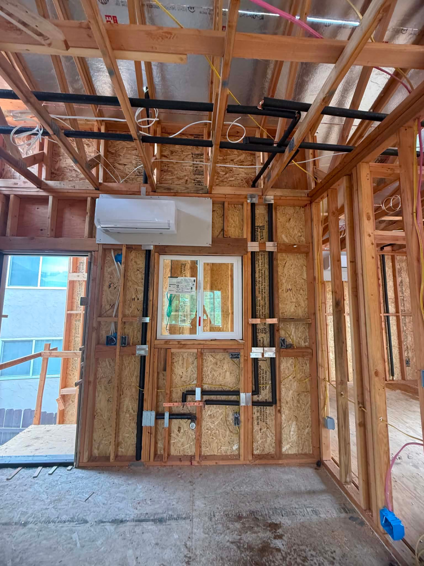 Rough-in plumbing with new water and drain lines run through framed walls